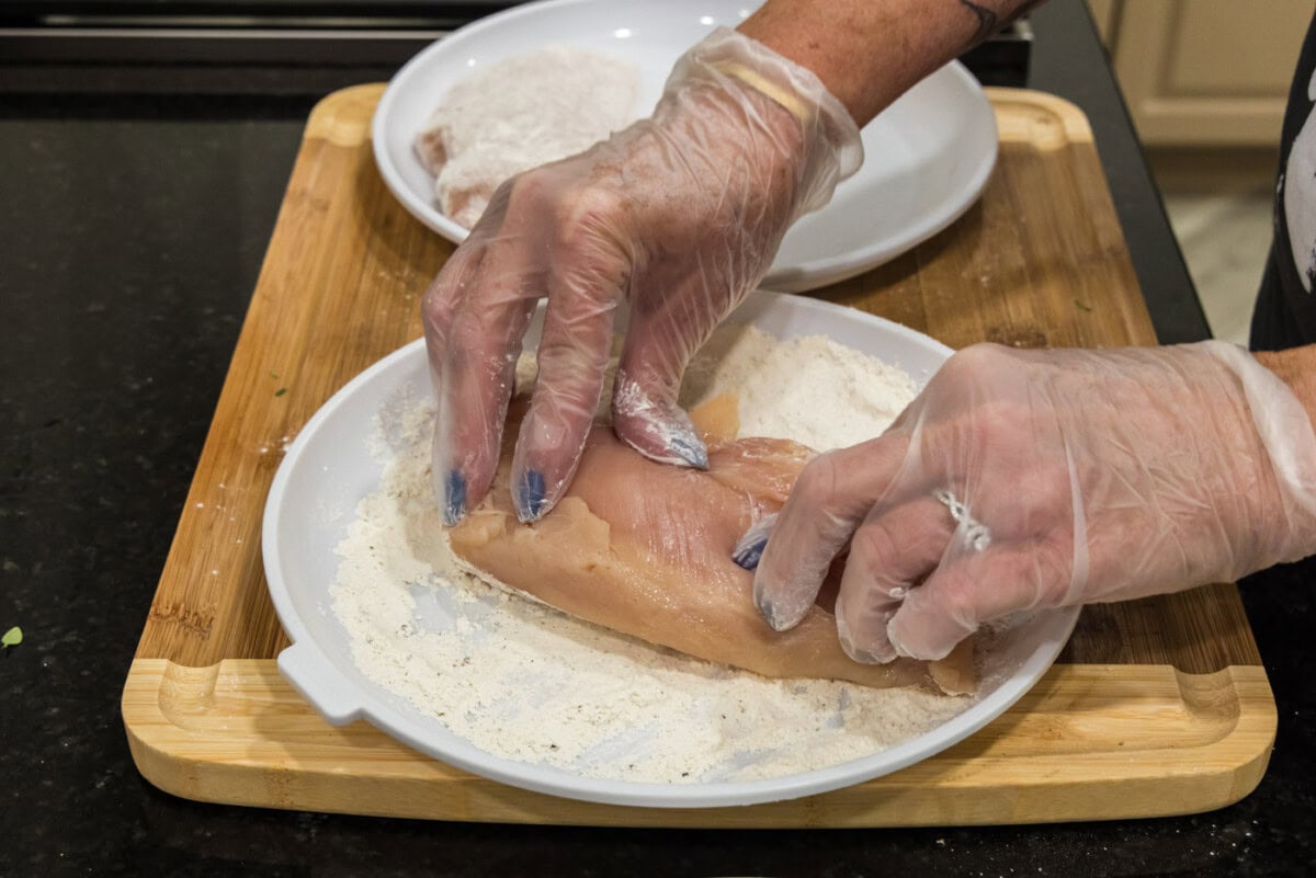 pressing chicken breasts into flour mixture