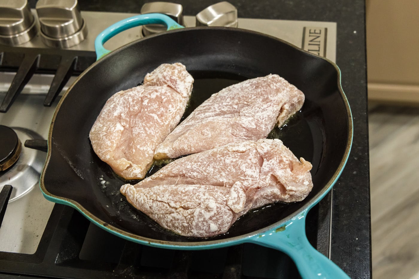 searing flour coated chicken breasts in a skillet