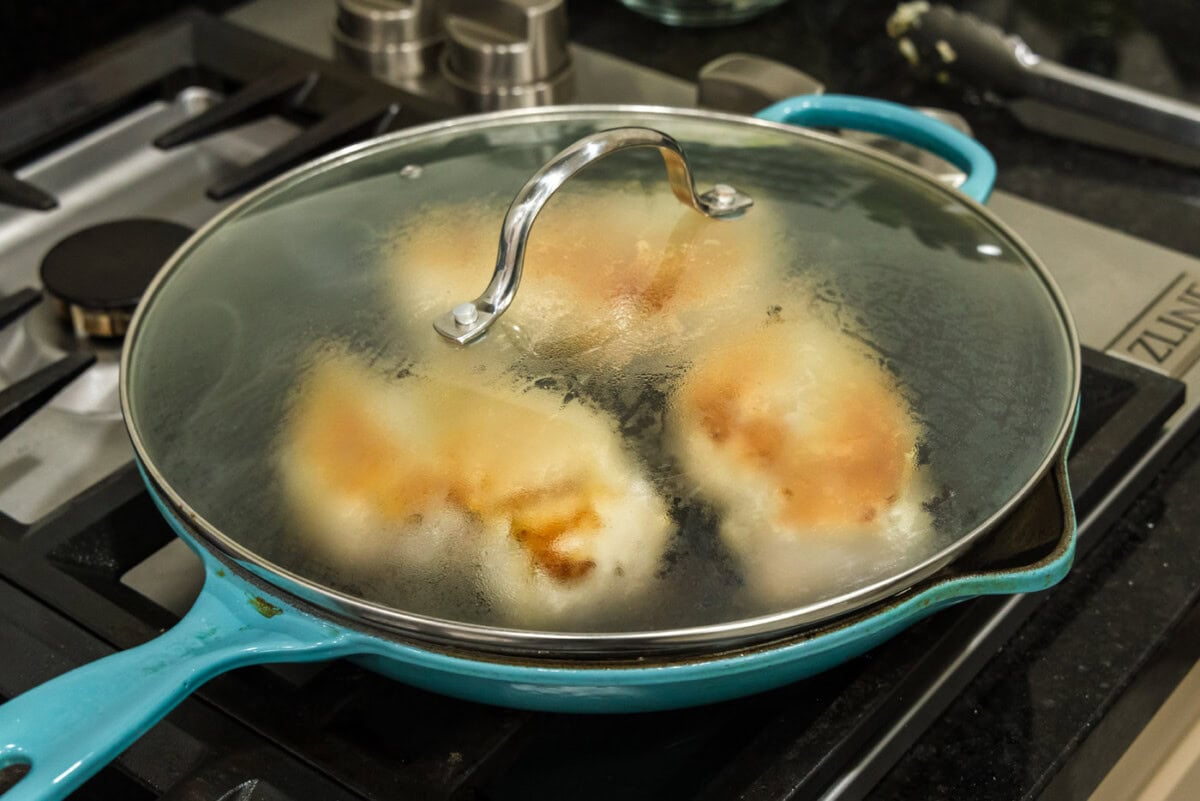 lid on skillet over chicken breasts