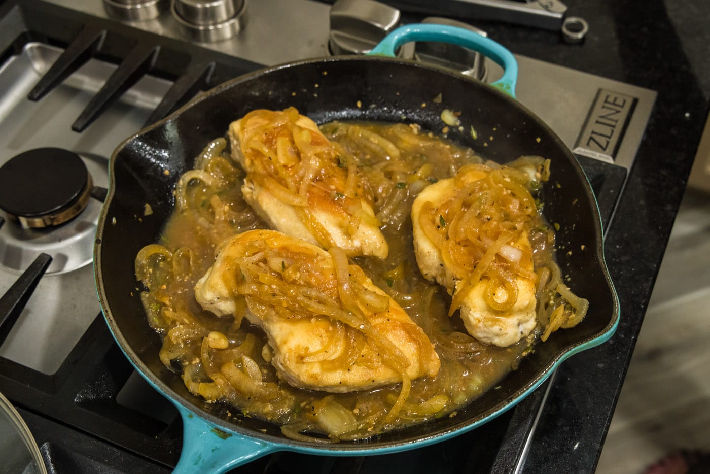 chicken breasts in a skillet with onion thyme sauce