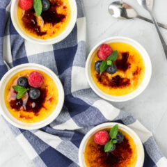 Four ramekins of Creme Brulee topped with fruit