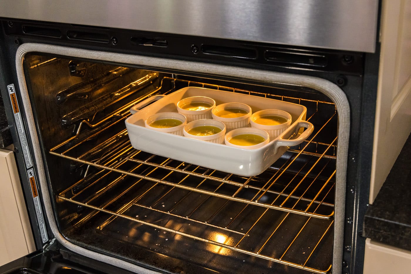 custard in ramekins placed in the oven in a baking dish