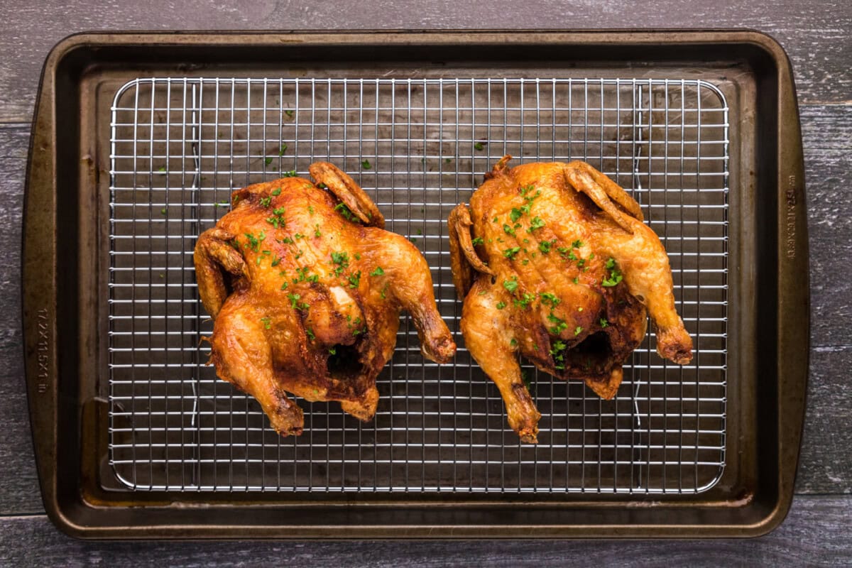golden skinned deep fried cornish hens on a wire cooling rack
