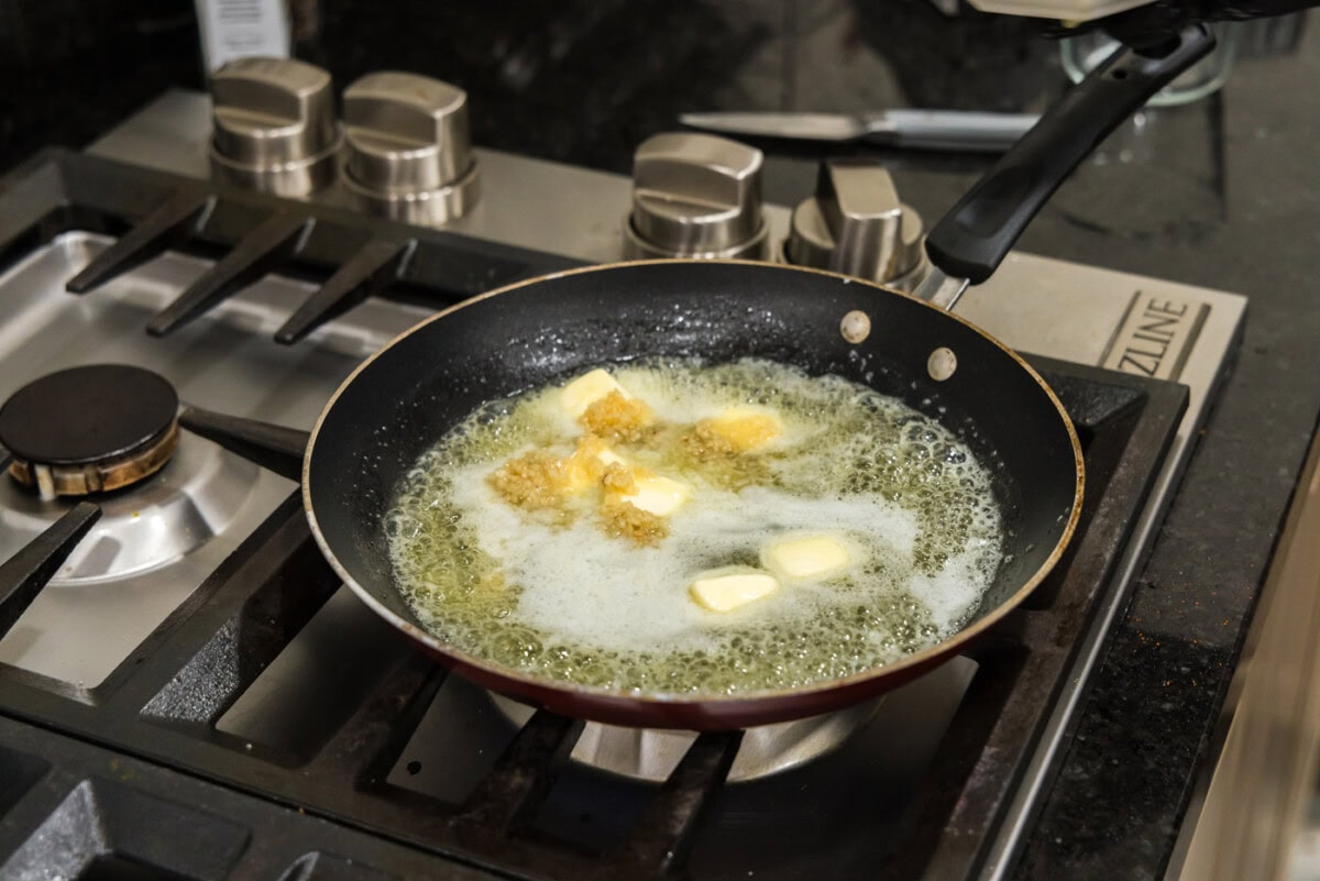adding minced garlic to skillet of melted butter