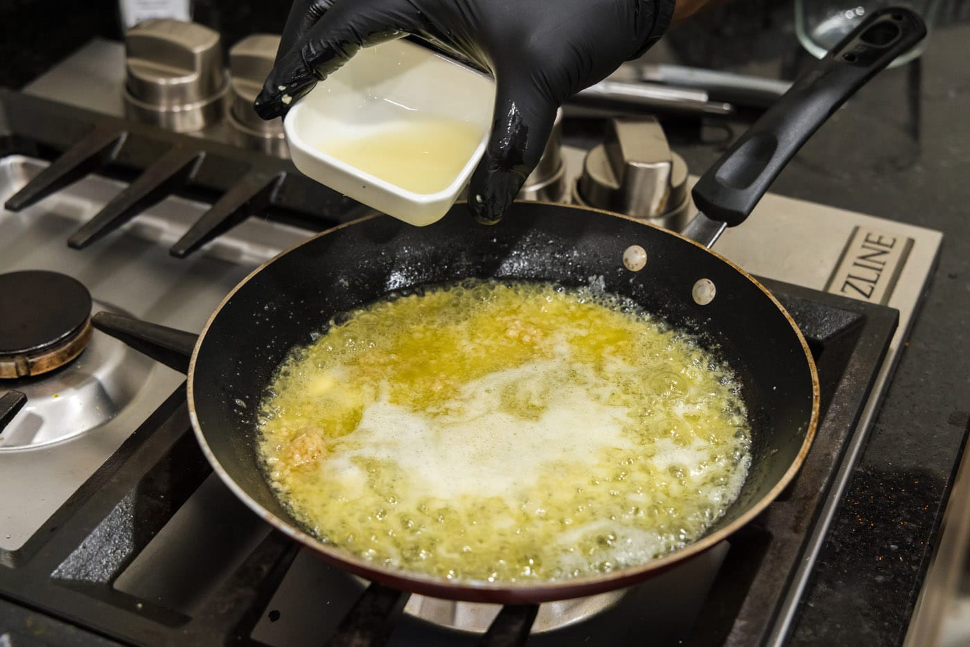 pouring lemon juice into melted butter and garlic mixture