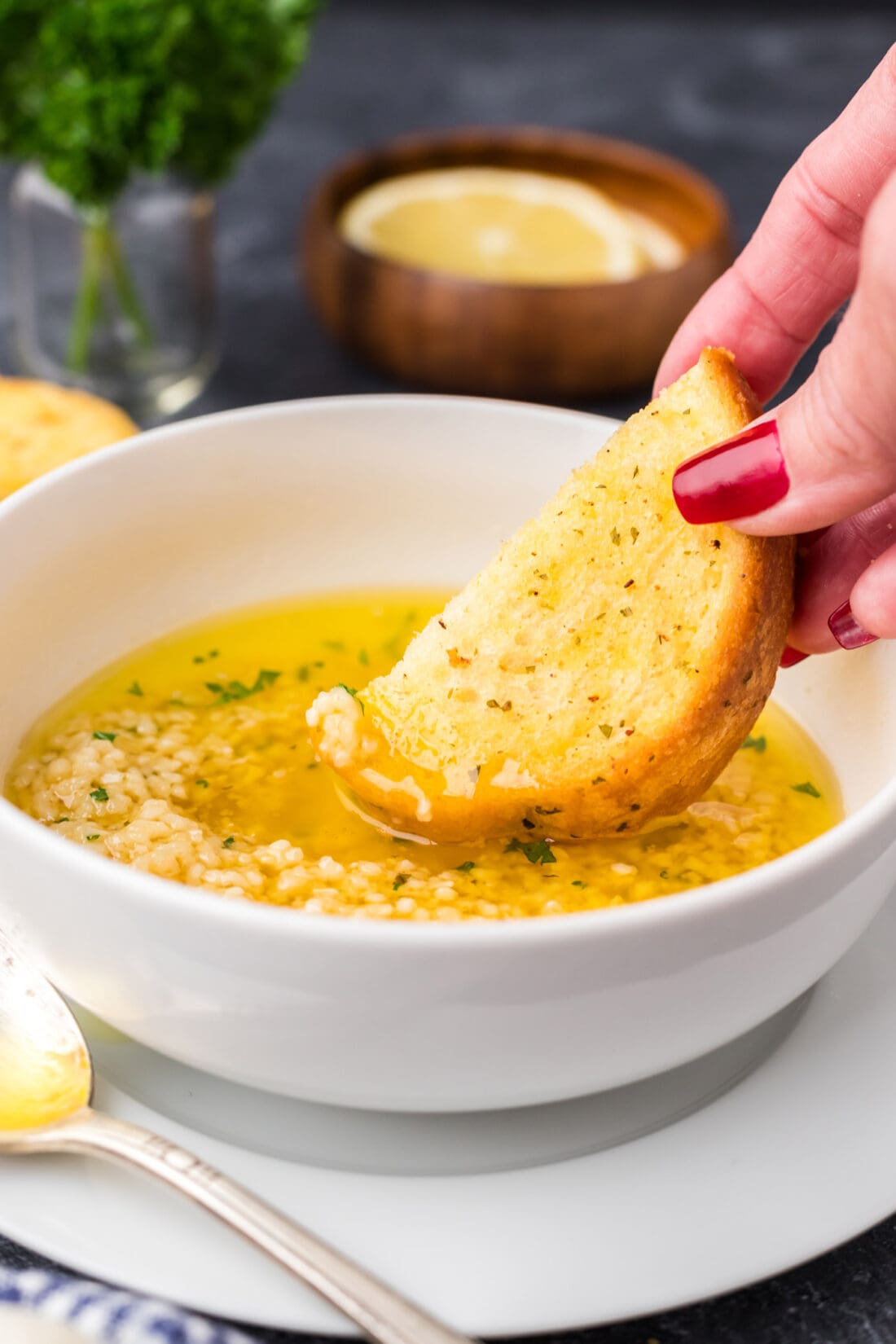 Piece of bread being dipped into Garlic Butter Sauce