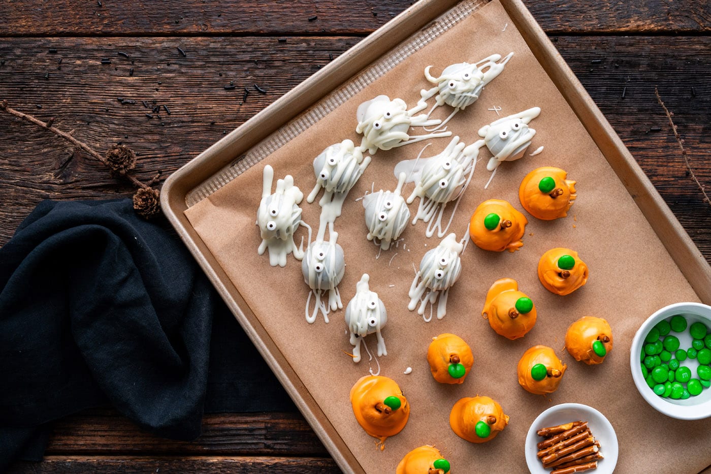 pumpkin oreo truffles on a baking tray with mummy truffles