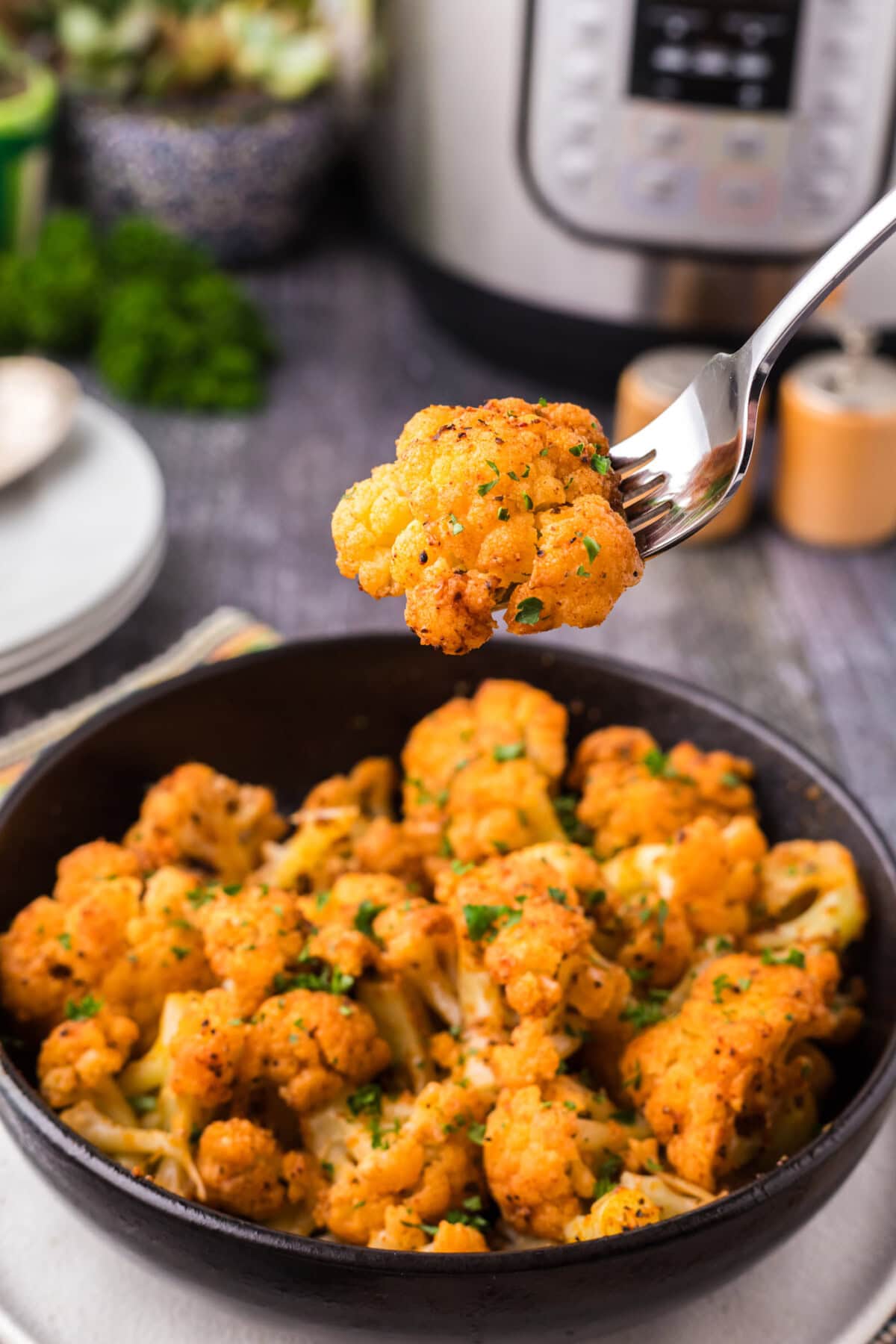 Piece of Instant Pot Cauliflower on a fork held above a bowl of Instant Pot Cauliflower