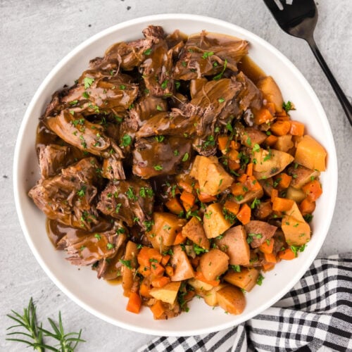 Bowl of Instant Pot Roast Beef with potatoes and carrots on the side