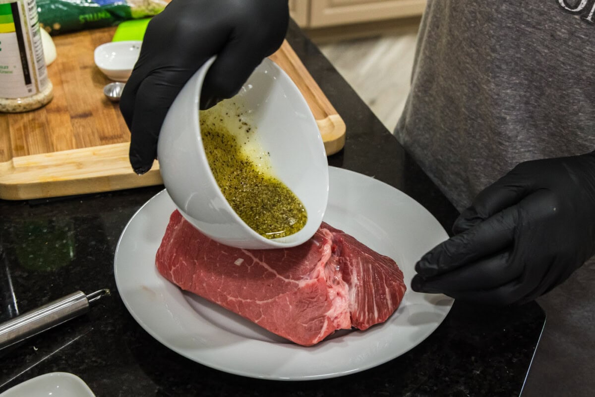 pouring wet rub on top of sirloin tip roast