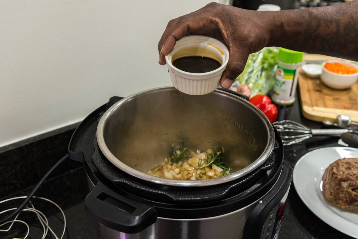 pouring soy sauce into instant pot with onion. mixture