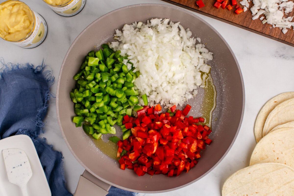 diced bell peppers and onion in a skillet with oil