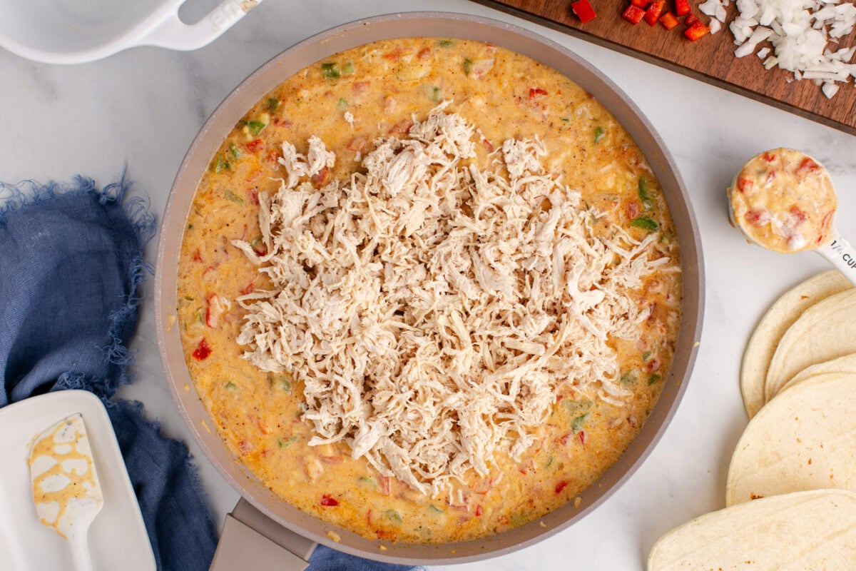 adding shredded chicken to sauce for king ranch casserole