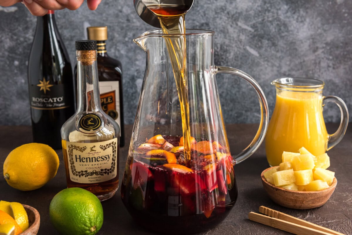 pouring brandy into red wine in a pitcher