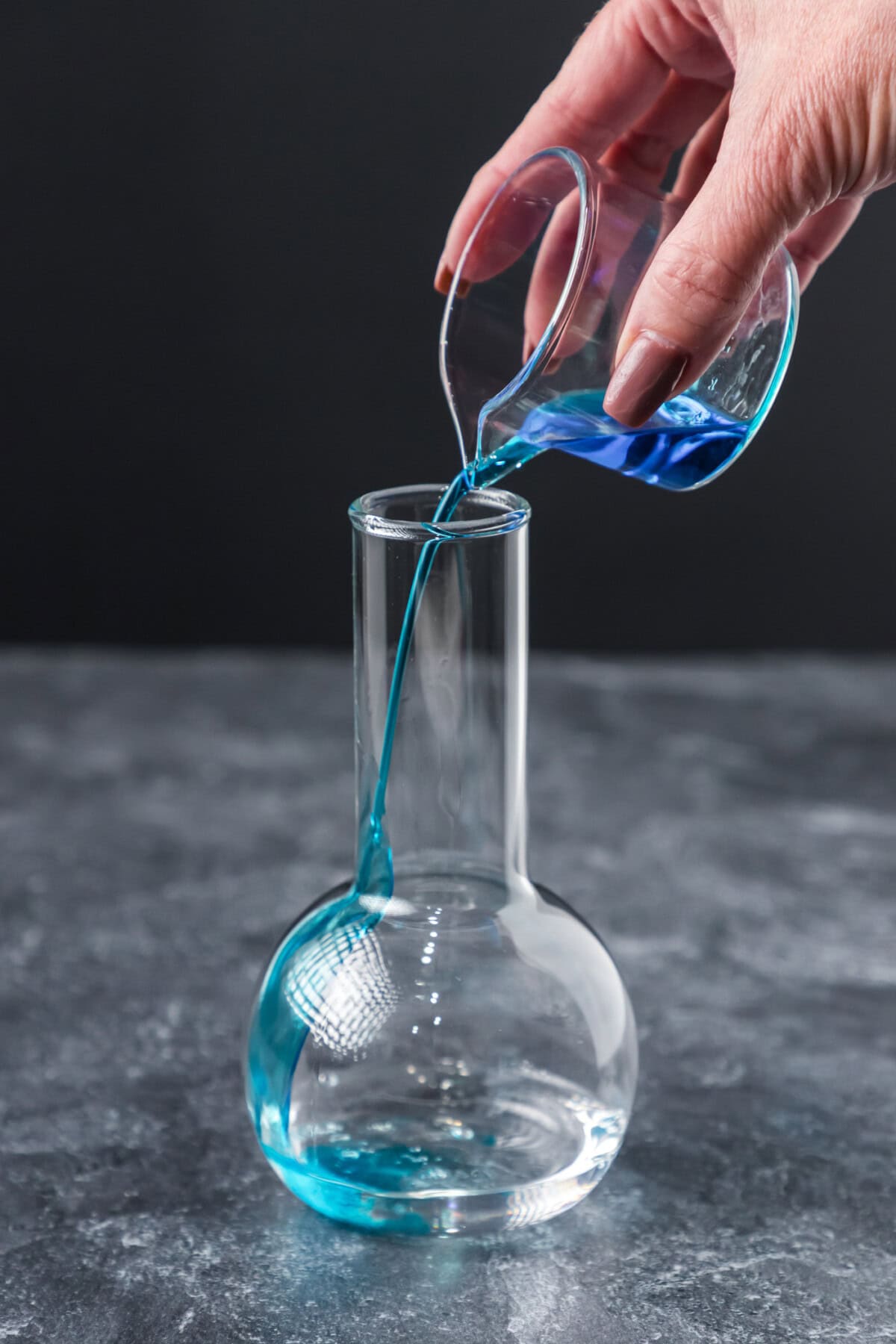 pouring blue curacao into cocktail glass