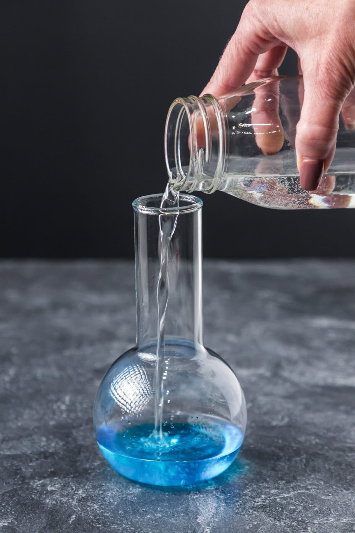 adding lemon lime soda to cocktail glass with blue curacao and coconut rum