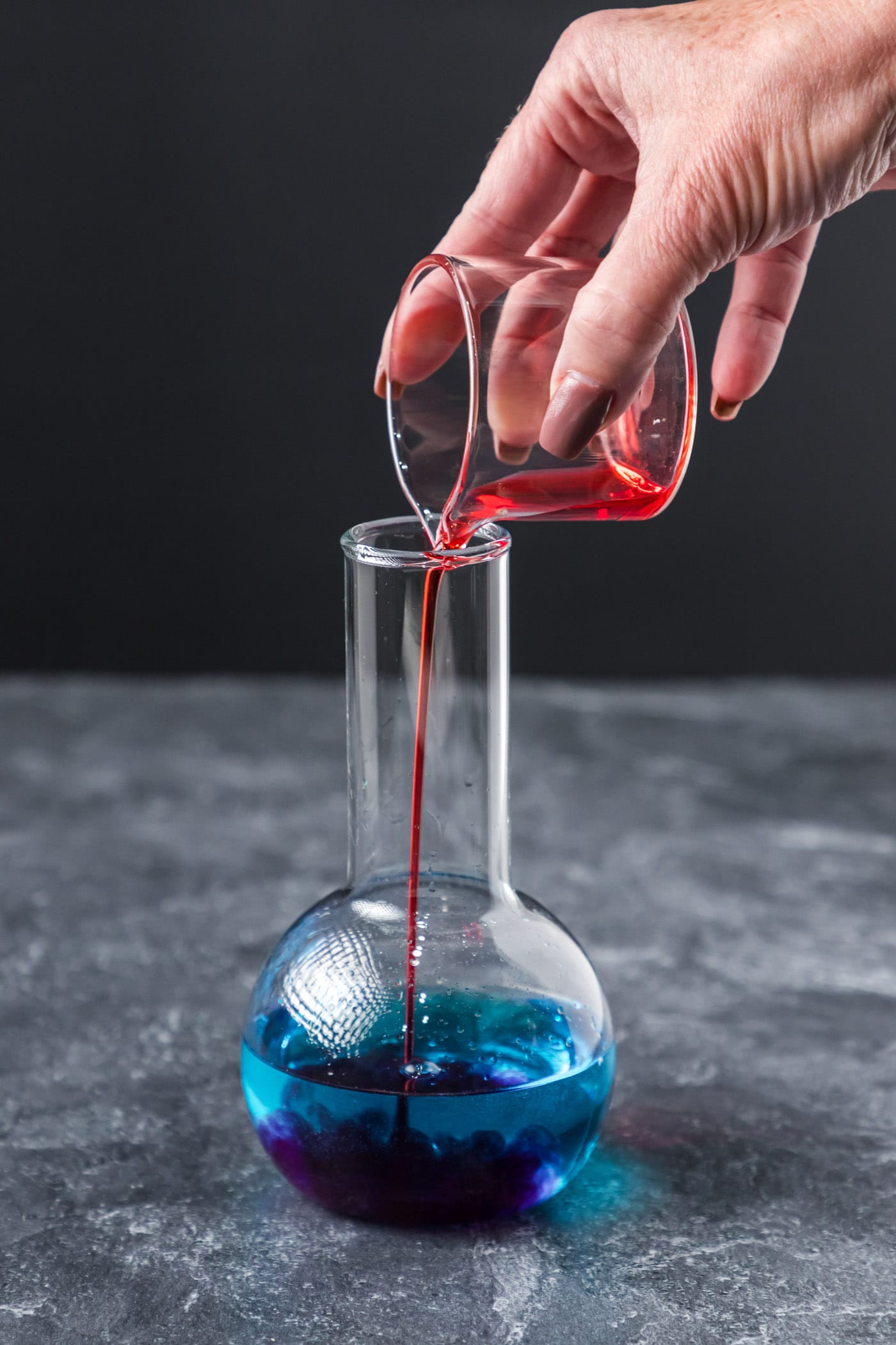pouring grenadine into cocktail glass with blue curacao and coconut rum