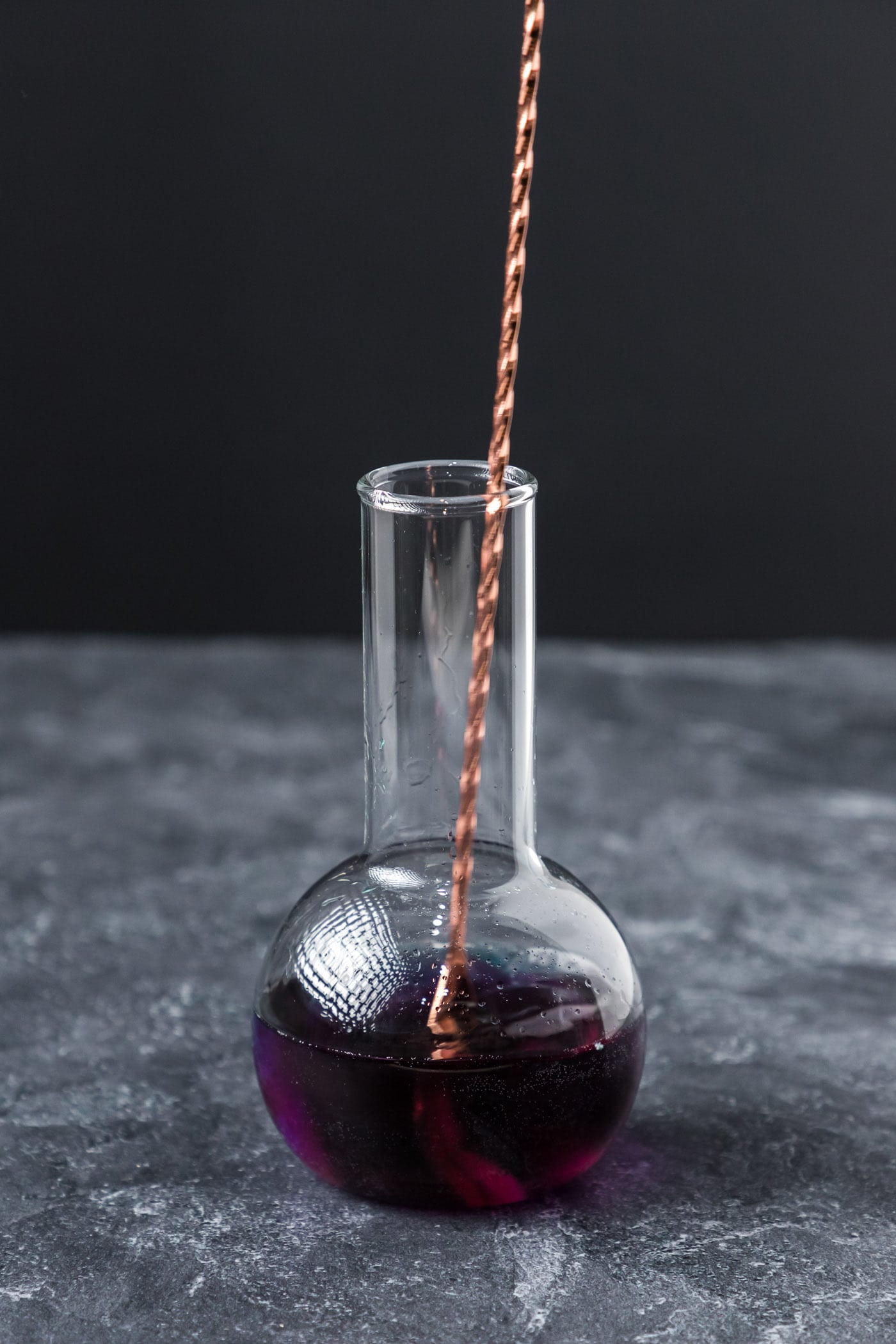 stirring purple people eater in a beaker cocktail glass