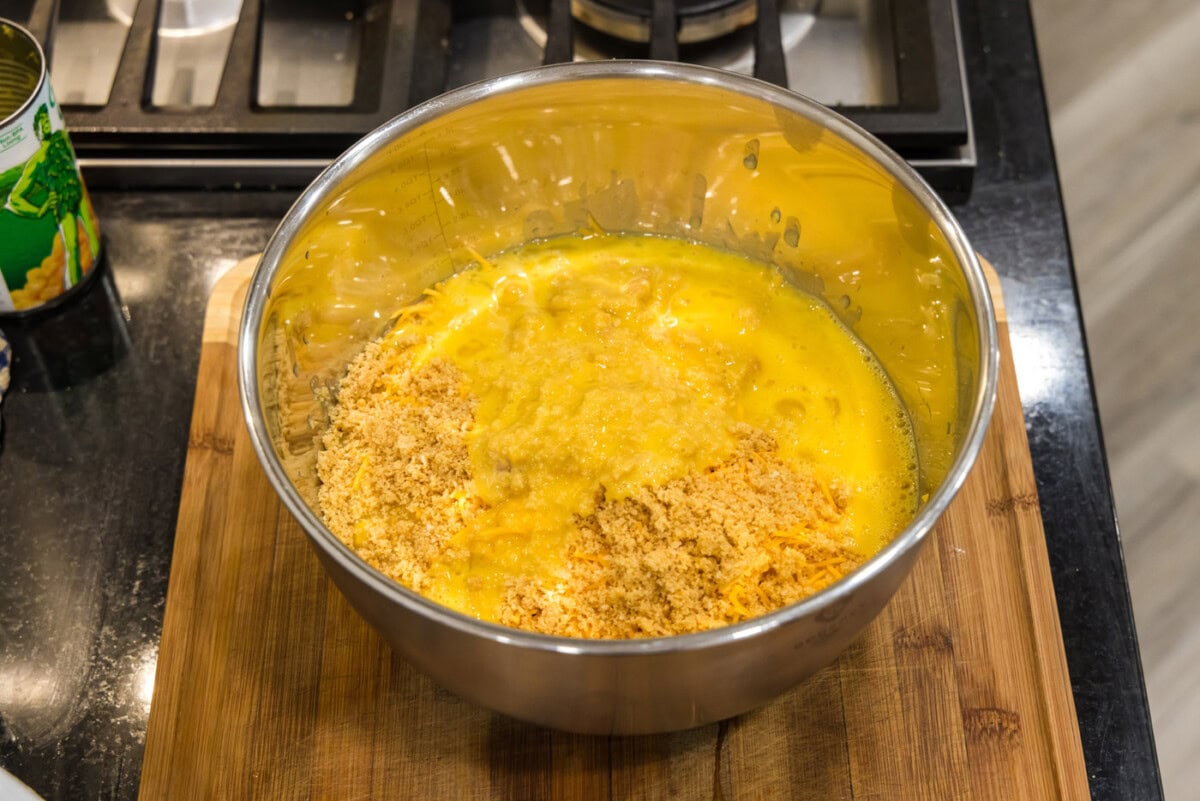 ritz crackers added to corn and cheese in a bowl