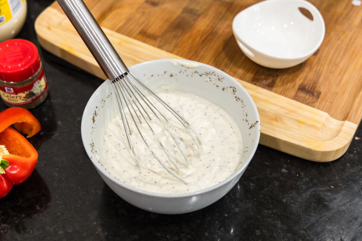 whisking shrimp pasta salad ingredients in a bowl
