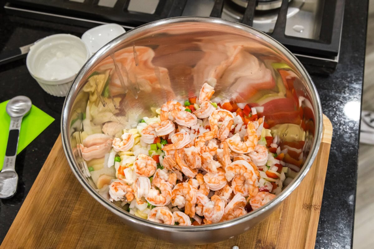 cooked shrimp added to bowl of pasta and veggies
