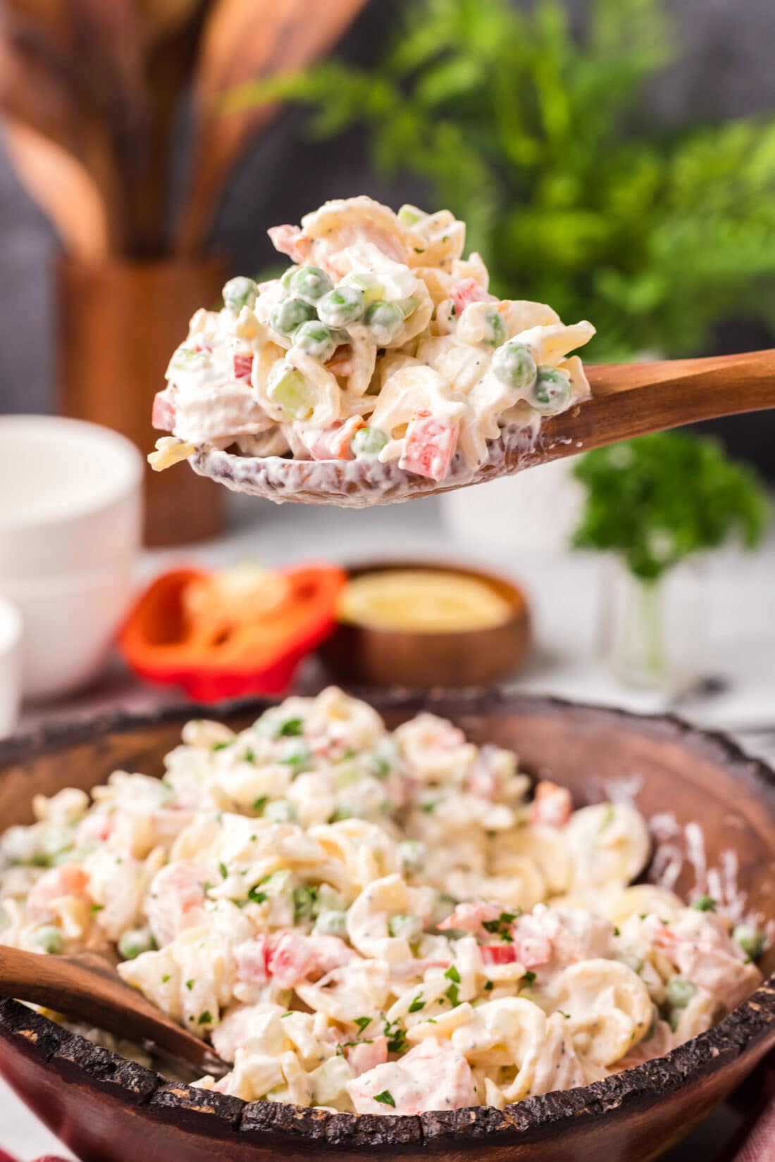 Spoonful of Shrimp Pasta Salad lifted above a bowl of Shrimp Pasta Salad