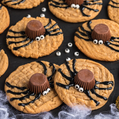 Spider Cookies on a black platter with candy eyes scattered around