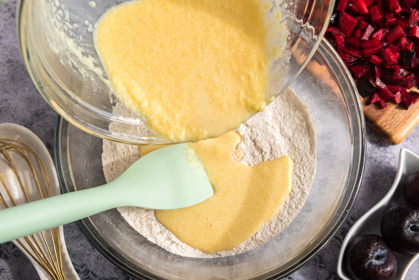 pouring egg mixture into dry ingredients for muffins