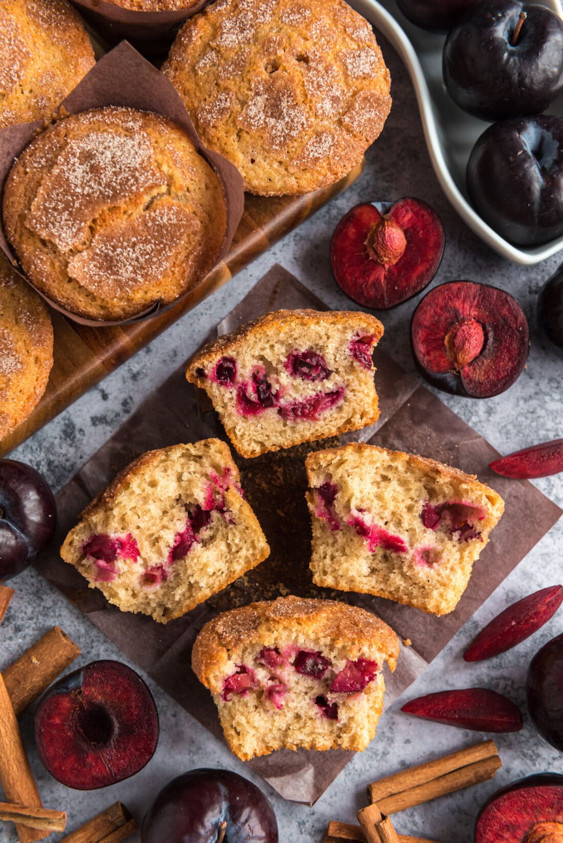 Two Sugar Crusted Plum Muffins cut in half on parchment paper