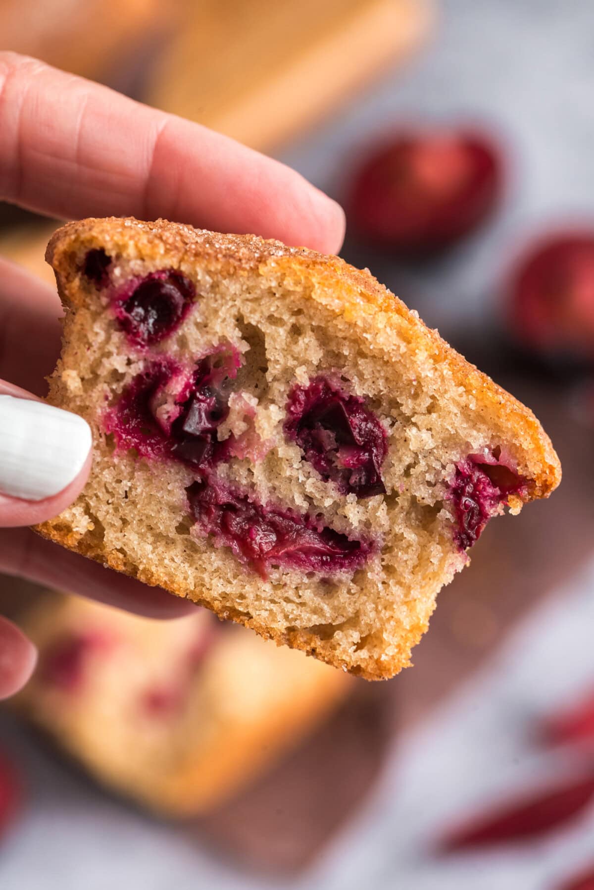 Hand holding half of a Sugar Crusted Plum Muffins