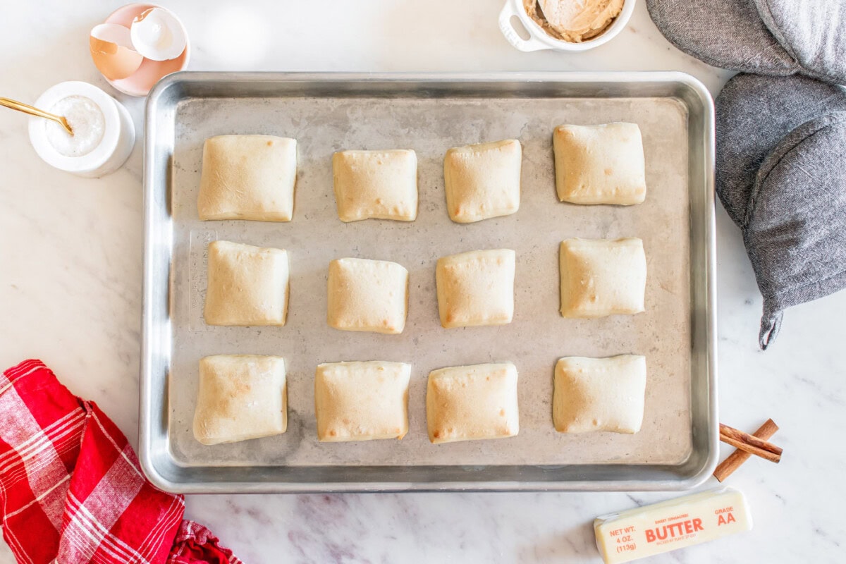 baked square shaped dinner rolls on a baking sheet