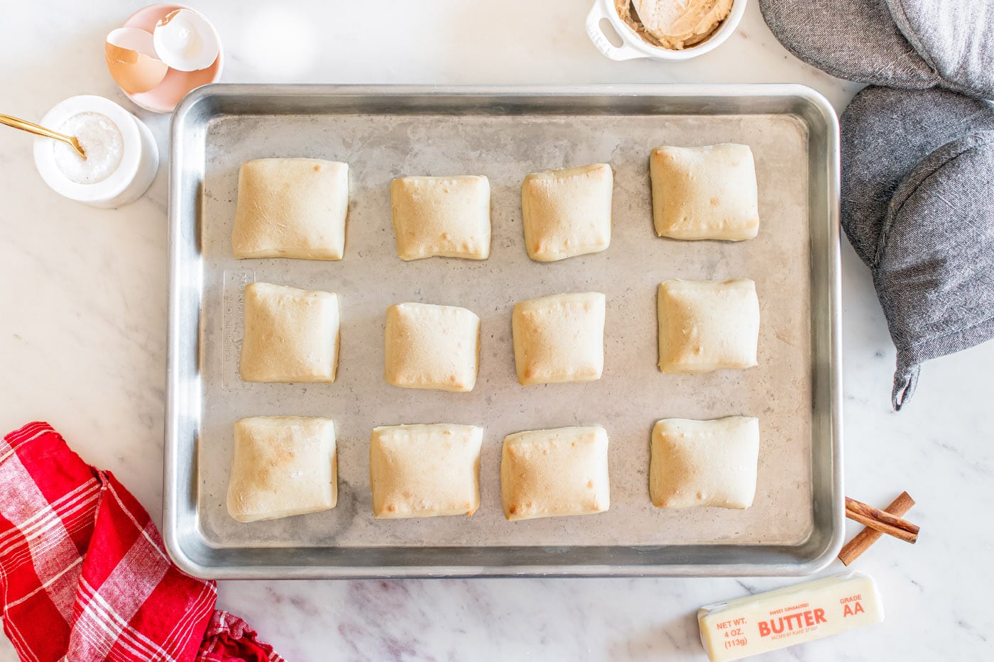 baked square shaped dinner rolls on a baking sheet