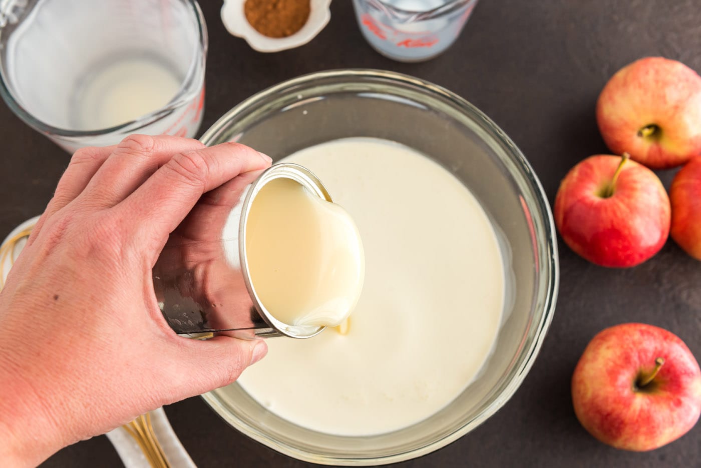 pouring sweetened condensed milk into bowl with heavy cream