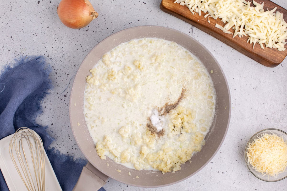 adding milk, salt, and pepper to skillet of onion and garlic