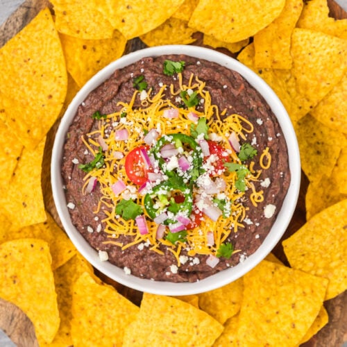 Overhead photo of a bowl of Black Bean Dip with tortilla chips around it