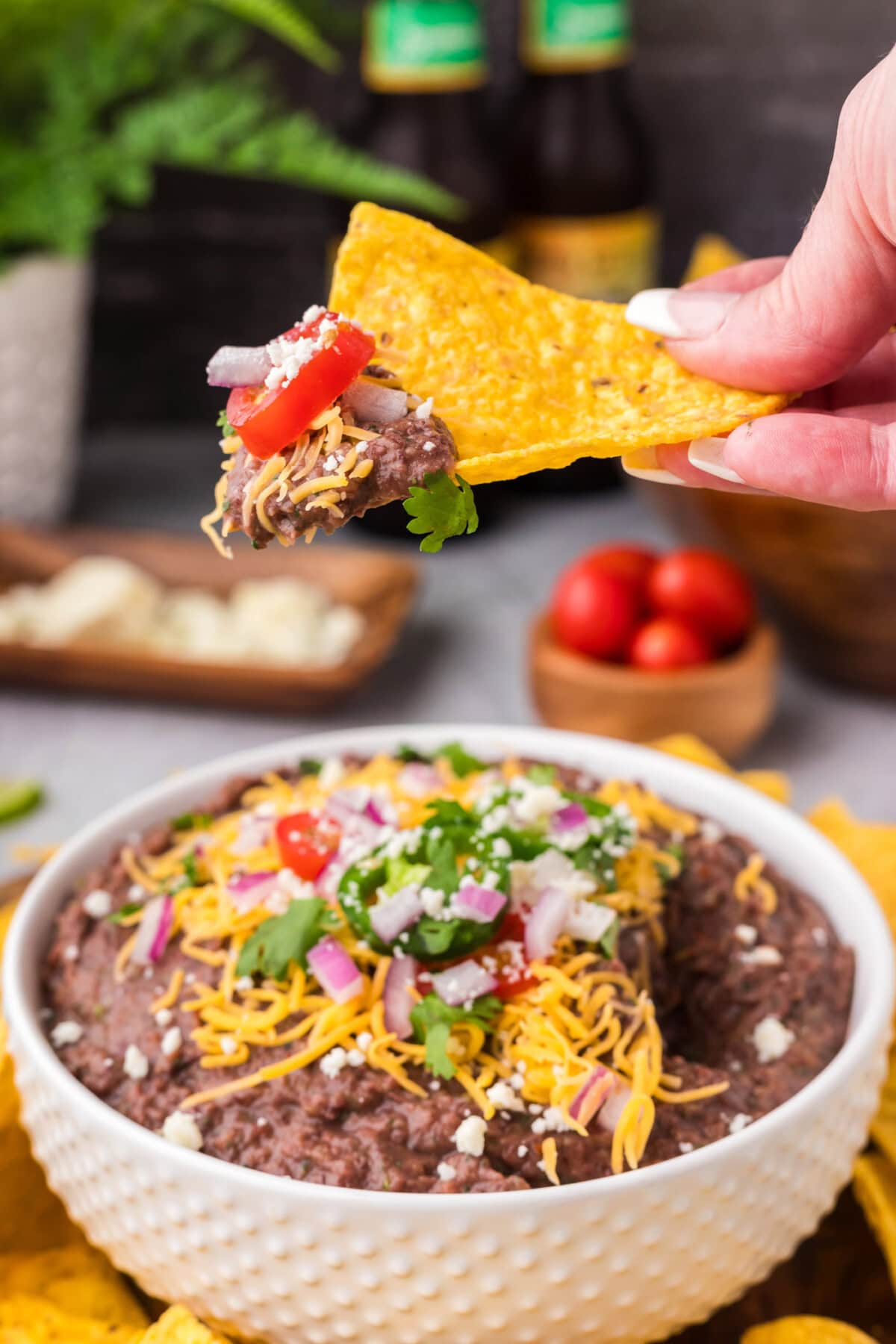 Black Bean Dip on a tortilla chip held above a bowl of Black Bean Dip