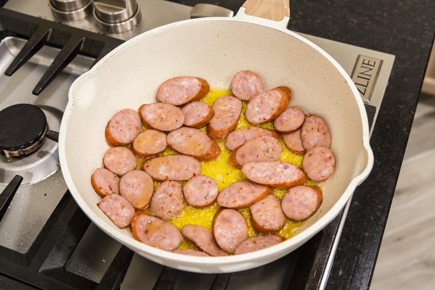 sliced andouille sausage in a skillet with oil