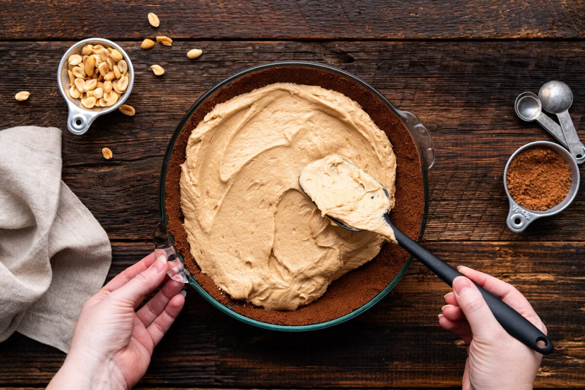 spreading peanut butter pie filling over chocolate graham crust