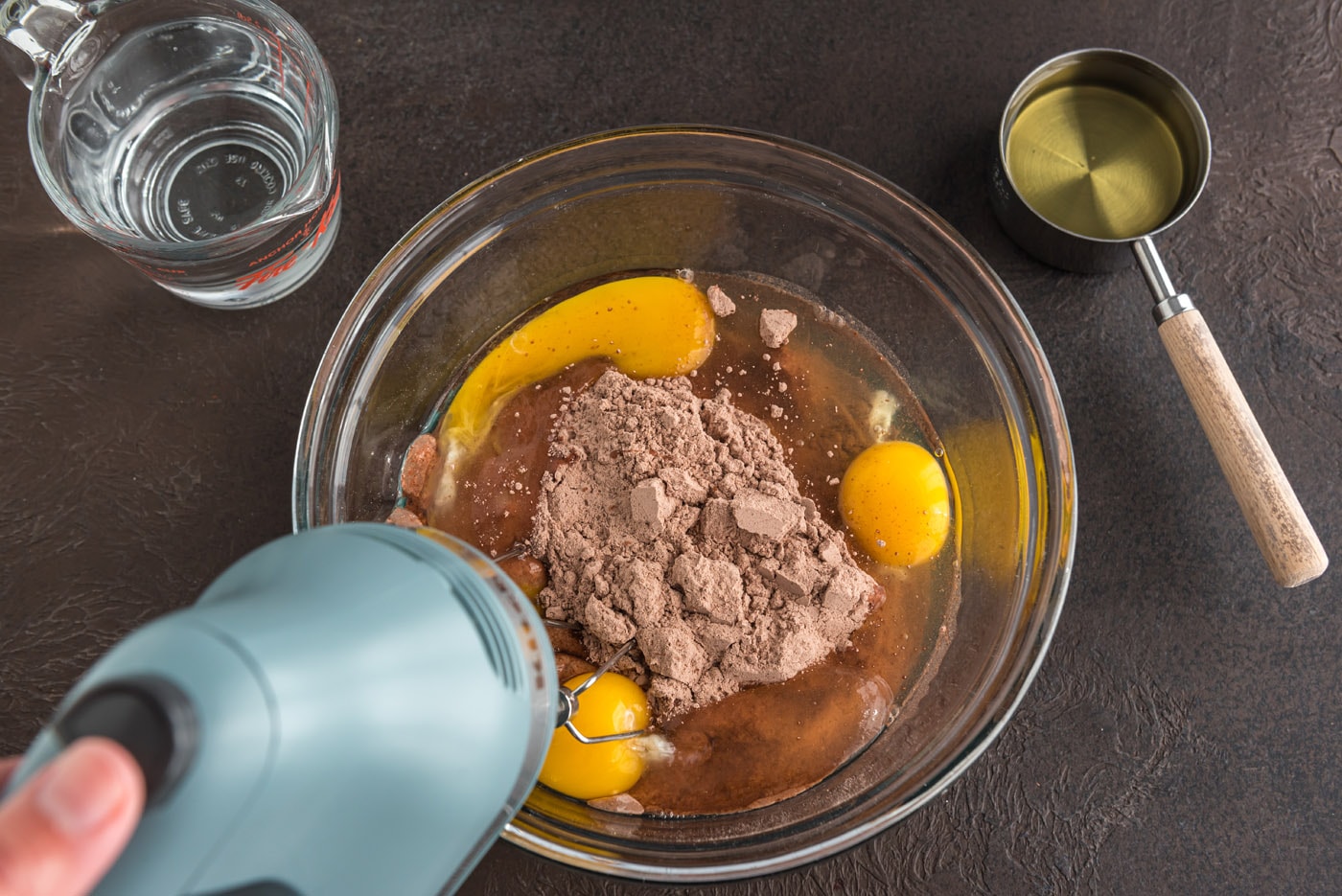 mixing cake mix with eggs, oil, and water with an electric mixer