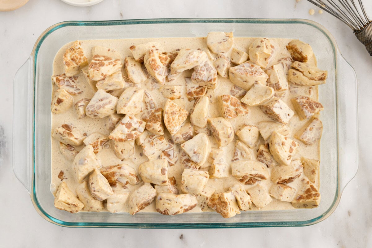 cream mixture poured over chopped cinnamon rolls in a baking dish