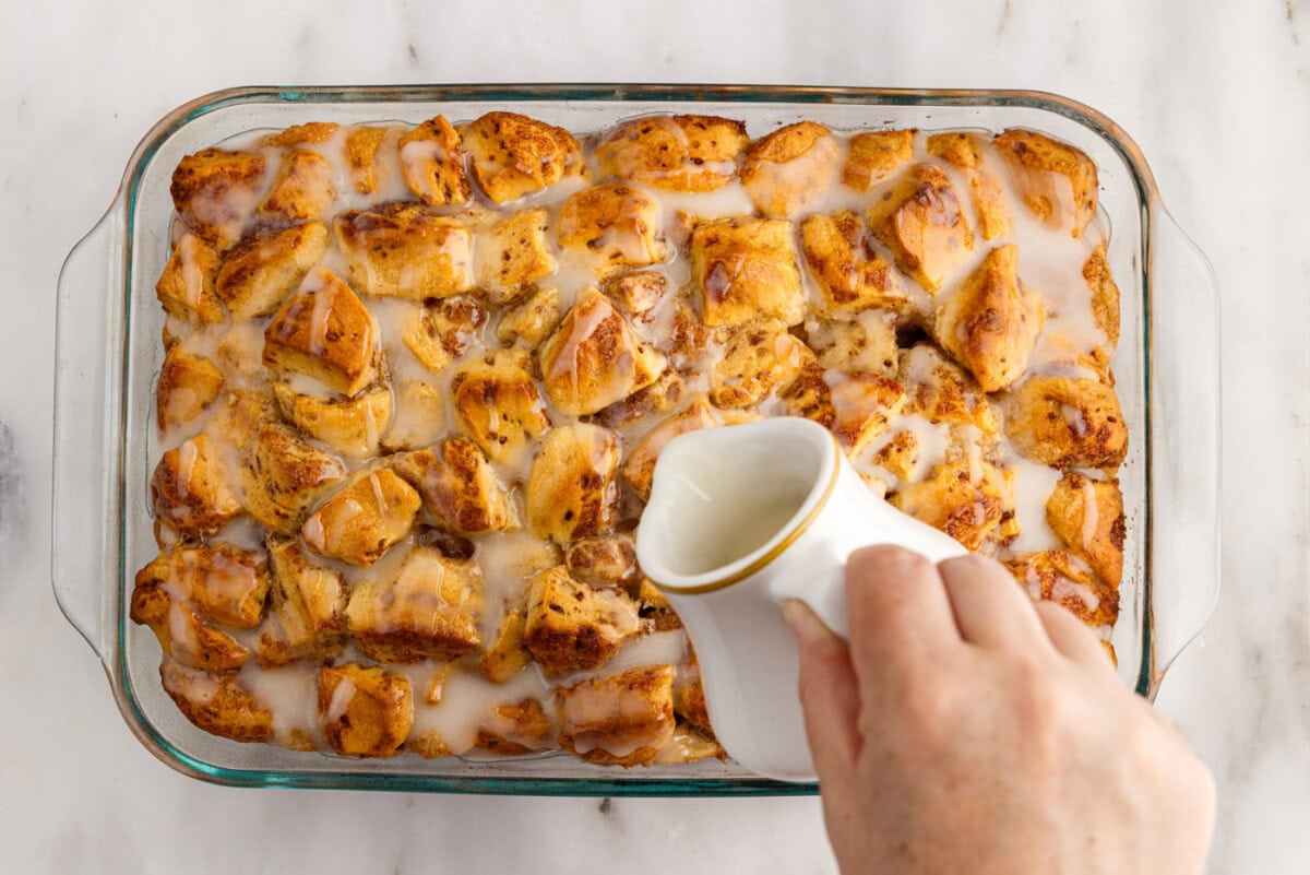 pouring icing over cinnamon roll casserole