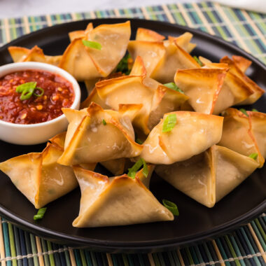 Close up photo of Crab Rangoons on a plate with dipping sauce