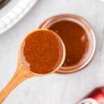 Close up photo of a spoon of Dr Pepper Barbecue Sauce held above a jar of Dr Pepper Barbecue Sauce
