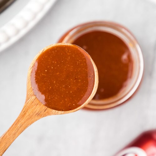Close up photo of a spoon of Dr Pepper Barbecue Sauce held above a jar of Dr Pepper Barbecue Sauce