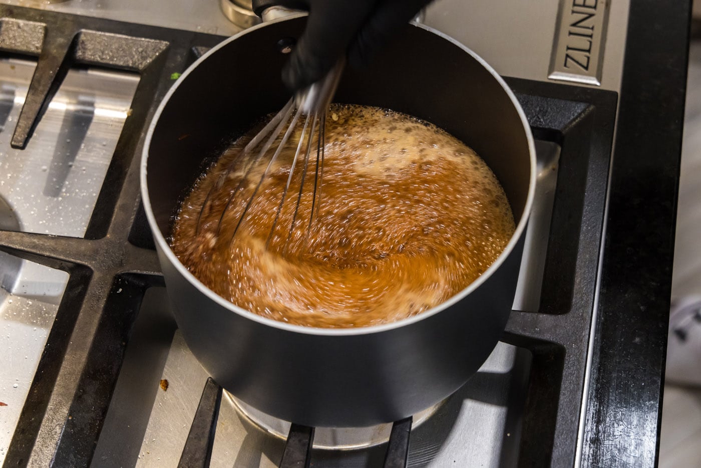 whisking cherry cola barbecue sauce ingredients in a saucepan