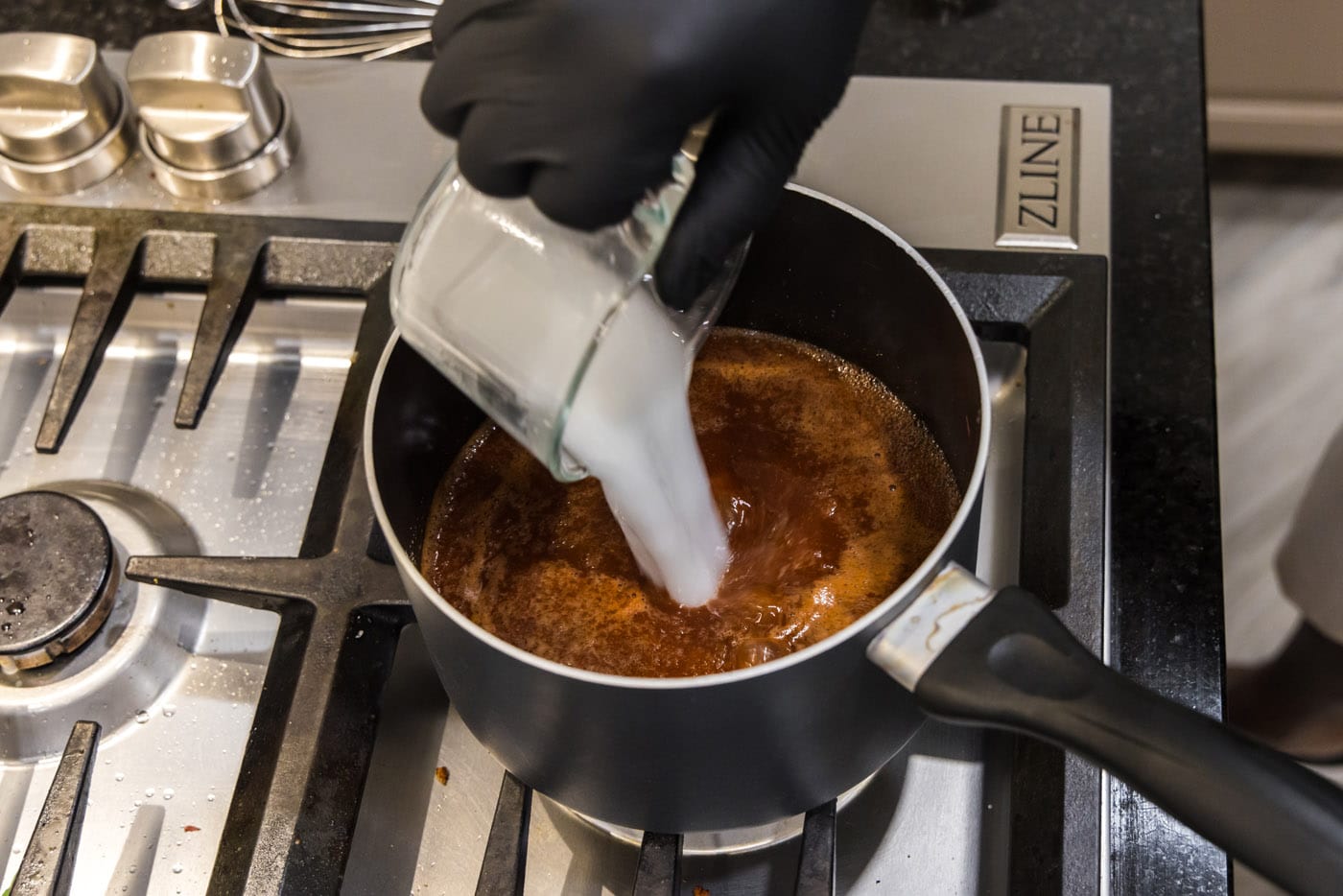 pouring a cornstarch slurry into barbecue sauce