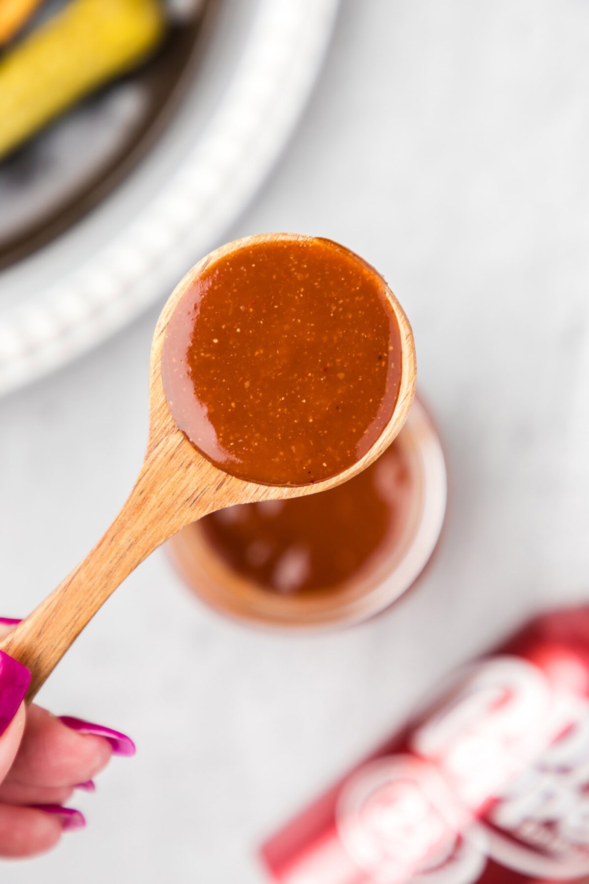 Spoonful of Dr Pepper Barbecue Sauce held above a jar 