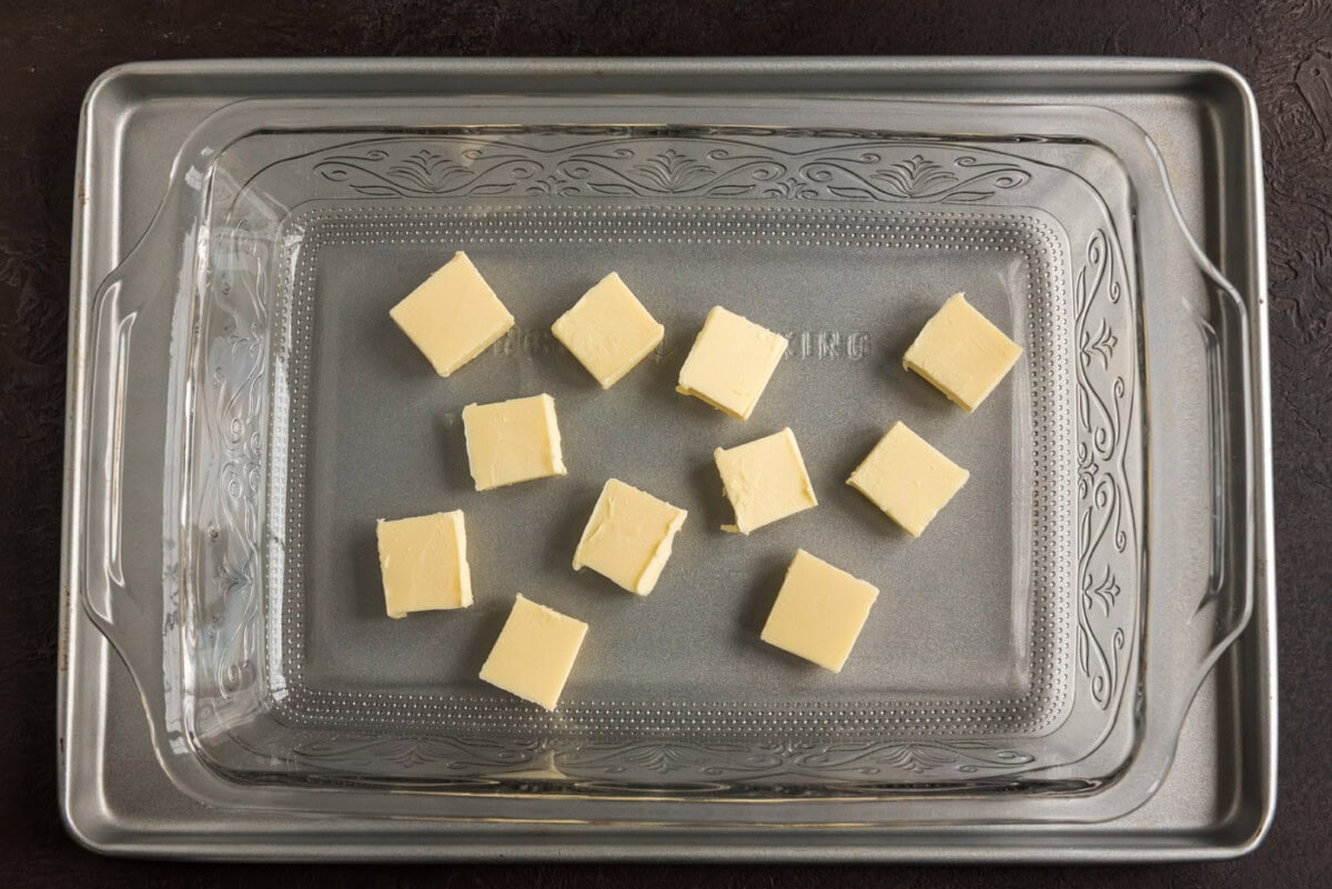 butter pats on the bottom of a baking dish