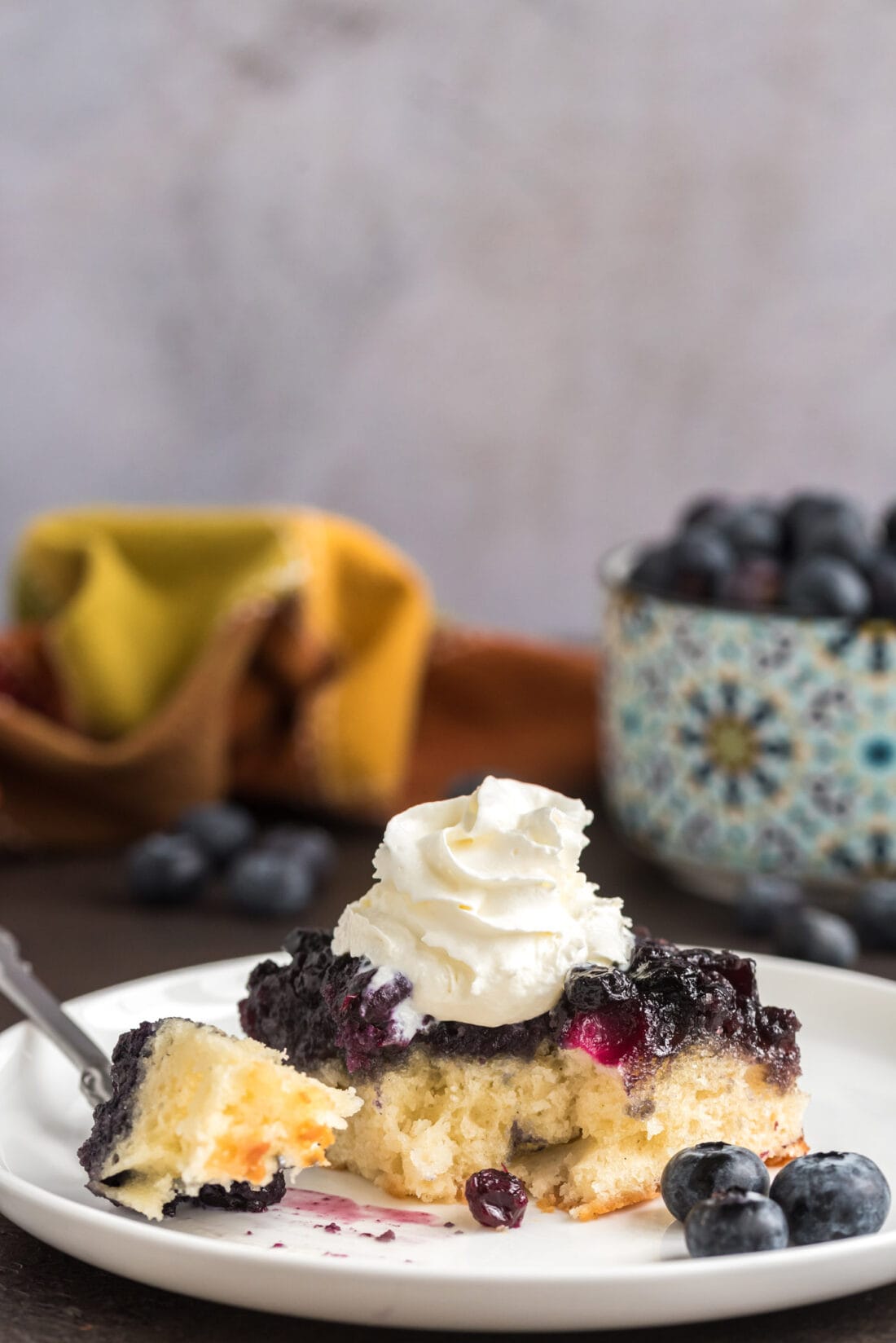 Piece of Easy Blueberry Upside Down Cake on a plate with a bite removed