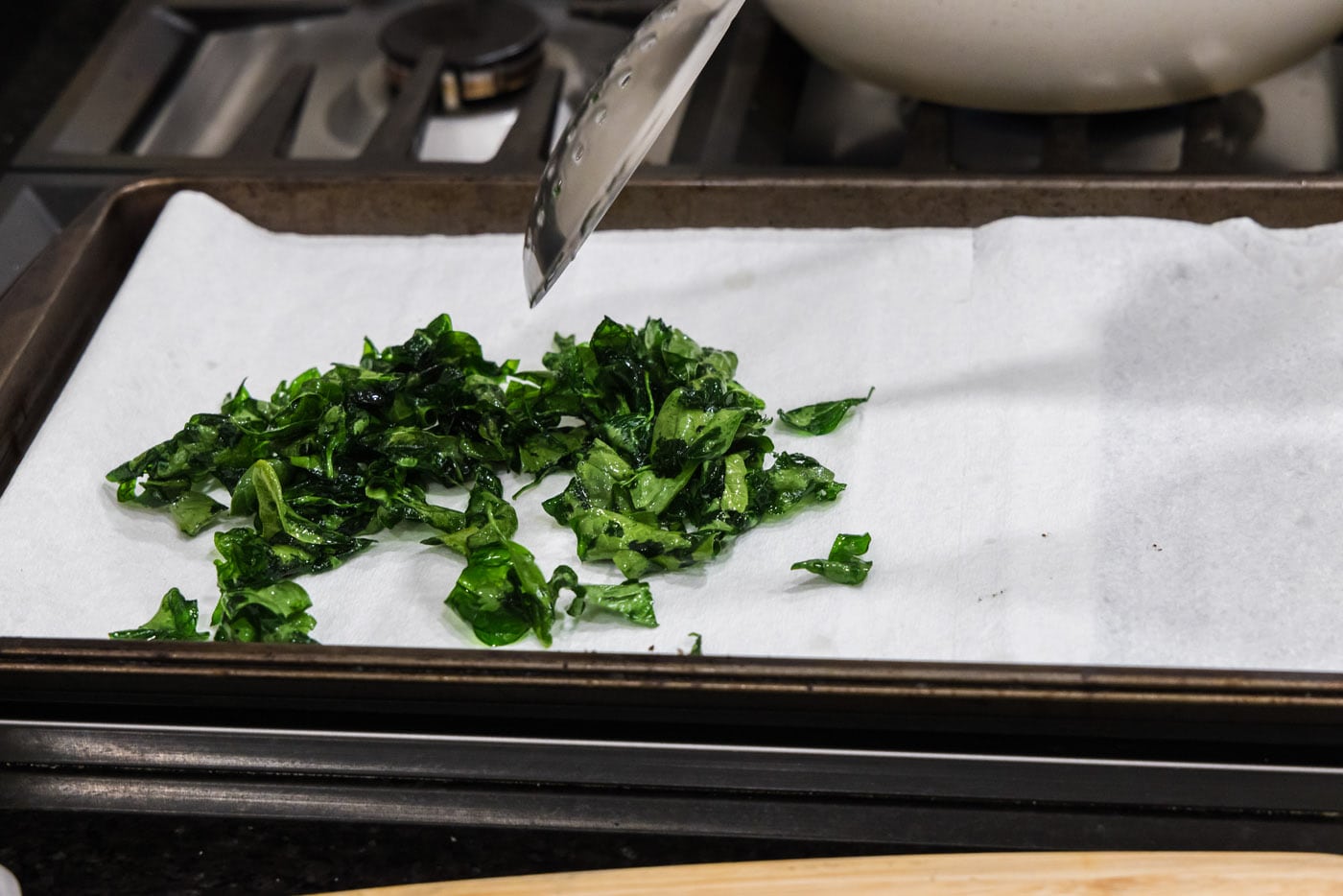 removing spinach from hot oil to drain on paper towels